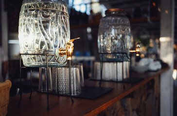 Two glass dispensers with metal tap and a lid