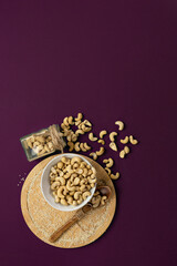 Top view of cashew nuts on a purple background.Copy space.Vertical format.