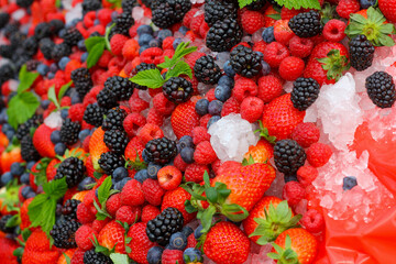 Blackberry, strawerry, raspberry, ice and green leaves background