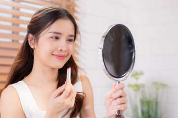 Beauty Asian woman using lipbalm in bedroom interior, lady taking care of her beautiful lips,