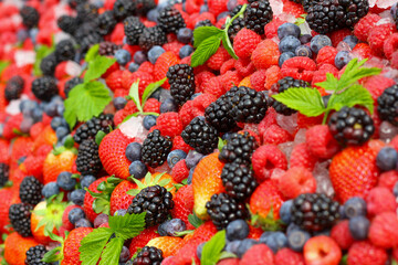 Blackberry, strawerry, raspberry, ice and green leaves background