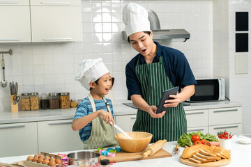 Happy moment asian father and son cooking breakfast in the kitchen. Dad and child asian family having fun preparing food bread egg sandwich. Positive parent and kid nice relationship