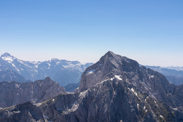 Panorama on top of untamed mountain peak mount Mangart (Mangrt), border Italy Slovenia. Scenic view of majestic mountain peaks of Julian Alps, blue sky summer day. Climb rugged extreme alpine terrain