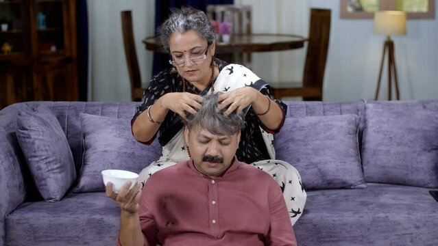 An old Indian lady is giving an oil massage to her tired husband - relaxation  caring wife  old couple  champi  salt and pepper look  oiling  healthy hair  hair care. An elderly couple - quality ti...