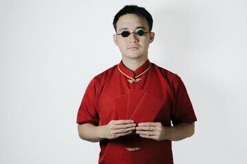 Asian man wearing traditional costume is holding angpao or red monetary gift and looking at the...