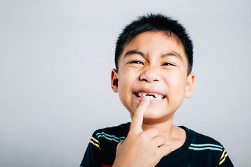 Six year old schoolboy happily points to growing molar gap. cheerful cute portrait child journey in...