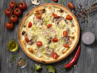 Flat lay pizza with bacon,cherry tomatoes,chicken breast on a wooden background.
