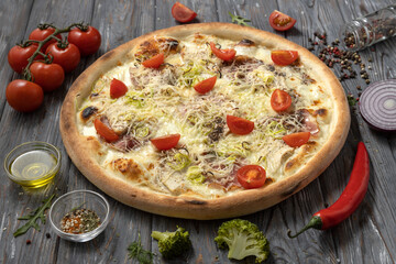 Appetizing italian pizza with bacon, cherry tomatoes,chicken breast on a wooden background.