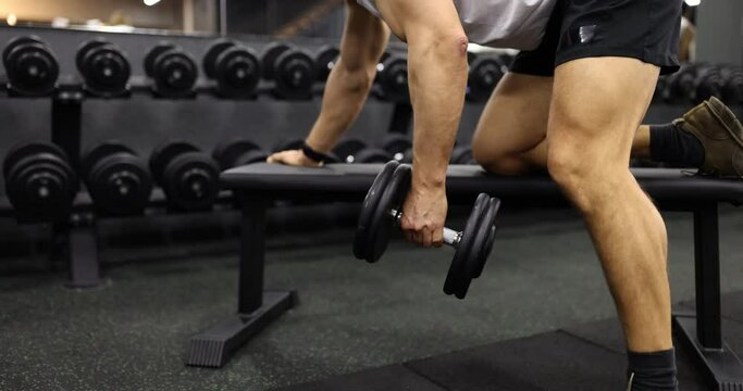 Man does lift holds heavy dumbbells in his hands and trains arm muscles. Training program in gym for man is set of strength exercises