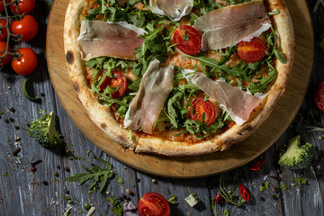 Close up pizza with bacon, arugula and cherry tomatoes.Top view