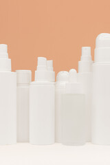 Facial skin care products on white table, assortment of cosmetic bottles on peach background, copy space. A clean ready-made template for brand presentation. Beauty ad