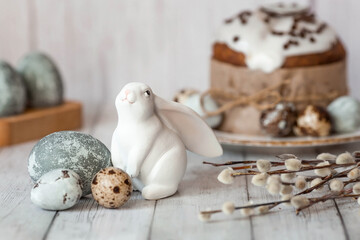 Stylish grey Easter eggs in the colors of marble, concrete, willow branches, Easter bunnies and Easter cake on a white wooden background. Coloring eggs for Easter. The feast of bright Easter.