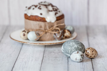 Fototapeta na wymiar Stylish grey Easter eggs in the color of marble, concrete, willow branches and Easter cake on a white wooden background. Coloring eggs with natural dye karkade tea. 
