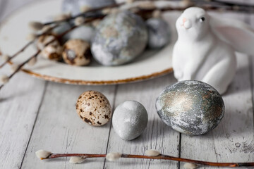 Stylish grey Easter eggs in the color of marble, concrete in a plate, willow branches and an Easter...