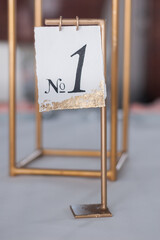 Wedding Table Number as a Stylish Decoration on Bridal Dinner. Sign showing first table number at wedding party. Vertical orientation. - 706329345