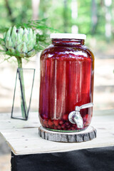 Homemade red drink in a glass jar on a wooden table. - 706331323