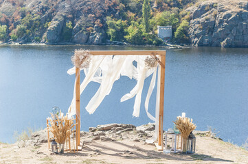 Riverside Elegance: A Wooden Arch Adorned with Flowers and Fabric, Creating a Stunning Setting for a Wedding Ceremony on the Edge of a Cliff Overlooking the River. - 706331369