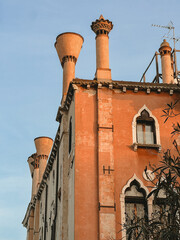 Old italian terracotta house with ornate windows and olive tree leaves 
