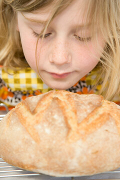 Young Girl Smelling a Loaf of Bread
