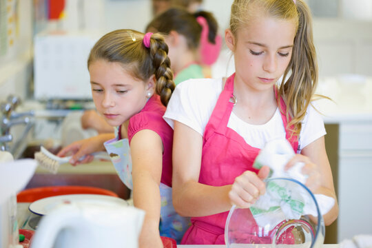 Young girls in cookery class washing up
