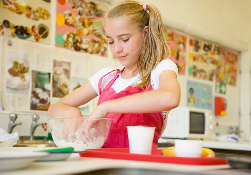 Young girl in cookery class kneading
