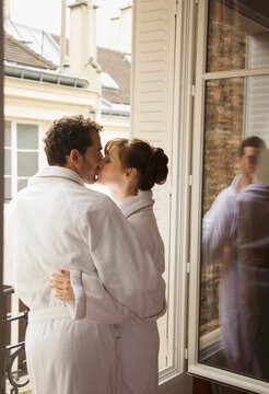Couple kissing in front of an open window
