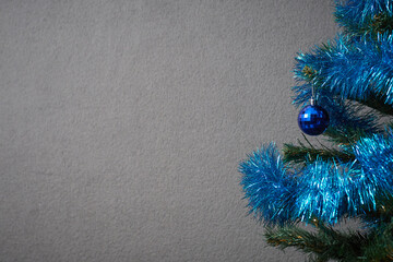 Photo of a Christmas tree decorated with a blue toy and New Year's tinsel for making a postcard