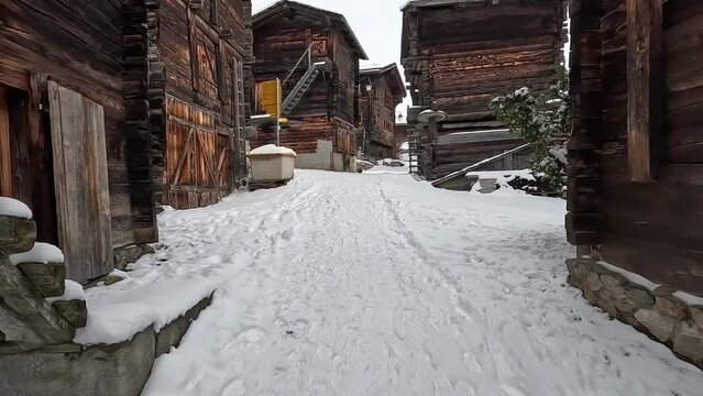 Bellwald in Switzerland. Snow-covered path leads through the middle of an old traditional Swiss village with huts and cabins