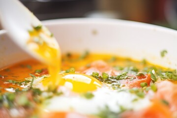 close-up of creamy yolk breaking into shakshuka sauce - obrazy, fototapety, plakaty