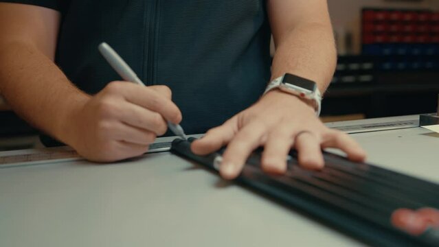 Male hands hold down golf club shafts and mark with pen for custom cutting and fitting on counter top in slow motion