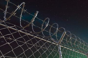Imposing Barbed Wire Fence Silhouetted Against a Star-Studded Night Sky