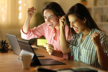 Excited tele workers in the night buying online celebrating
