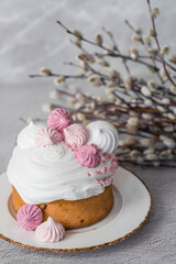 Beautiful stylish still life. Easter cake with meringue, marshmallows, Easter eggs and willow twigs on a light concrete background. happy Easter 2024.