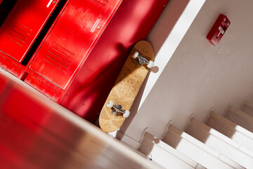 Skateboard by School Lockers on Sunlit Staircase: A Symbol of Youth