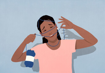Playful woman with face entangled in knitting yarn

