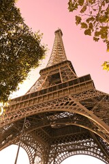 Vue en contre plongée sur la tour Eiffel fraichement repeinte, ciel rosé avec effet de couleurs nuancées 