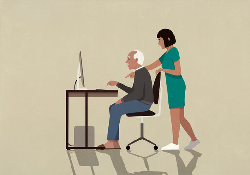 Granddaughter helping grandfather using computer at desk
