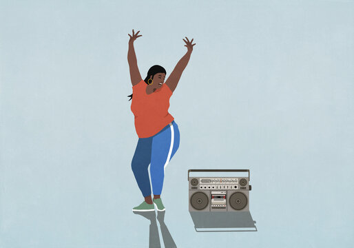 Carefree woman with arms raised dancing next to boom box on blue background
