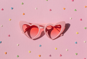 Heart shaped sunglasses on the pink background. Valentine's day concept composition
