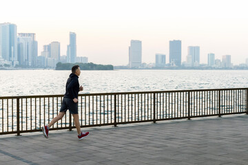 active senior man running outdoors on promenade by sea in early morning.