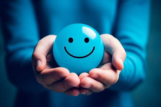 Hands holding a blue smiley face, symbolizing positivity and emotional satisfaction.