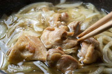 親子丼調理シーン。鶏肉と玉ねぎを卵とじするためだし汁で煮る。
