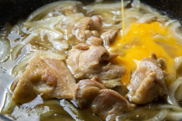 親子丼調理シーン。鶏肉と玉ねぎを卵とじする。
