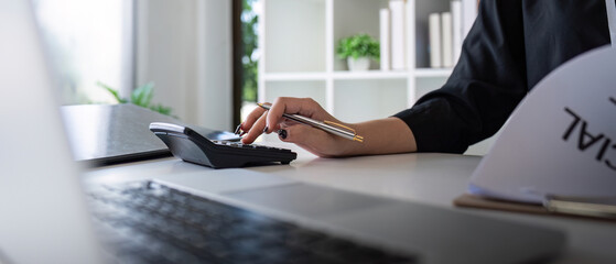 Obraz premium Businesswoman accountant using calculator and laptop for financial data saving in office room, Business financial, tax, accounting concept