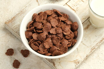 a bowl of sweet chocolate cereal flakes for breakfast on white background