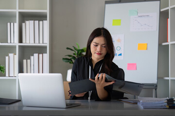 Entrepreneur or business woman working comparing documents with a computer laptop sitting in a desk at office