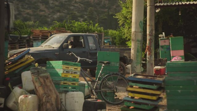 Old bicycle leans against shed and crates with old truck lit by afternoon light, Leonidio Greece