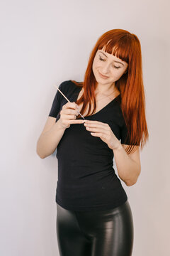 A captivating image capturing the allure of a red-haired woman confidently holding a pair of scissors.