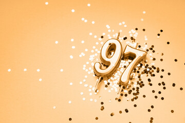 97 years celebration festive background made with golden candles in the form of number Ninety-seven lying on sparkles. Universal holiday banner with copy space.