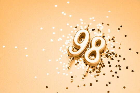 98 years celebration festive background made with golden candles in the form of number Ninety-eight lying on sparkles. Universal holiday banner with copy space.